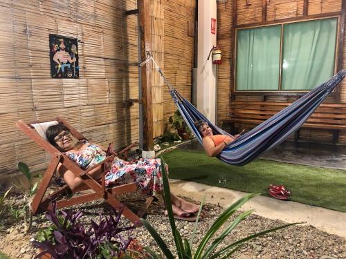 two women laying in hammocks in a yard at Qeru House in Zorritos