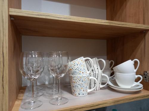 a shelf with wine glasses and dishes on it at Apartament przy Obozie in Oświęcim