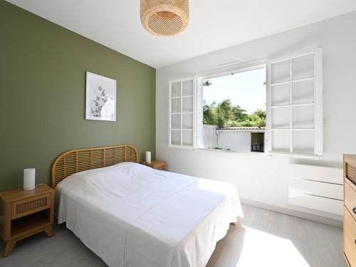 um quarto com uma cama branca e uma janela em Maison Ars-en-Ré, 3 pièces, 4 personnes - FR-1-434-101 em Ars-en-Ré