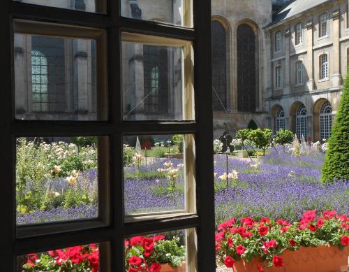 a window looking out at a garden with flowers at Hôtel de l'Abbaye des Prémontrés in Pont-à-Mousson