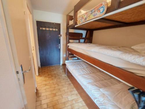 Cette chambre comprend 2 lits superposés et une porte. dans l'établissement Charmant Studio au Centre de Samoëns - Balcon Exposé Sud, Parking et Animaux Acceptés - FR-1-624-110, à Samoëns