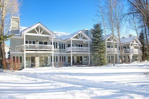 a large white house in the snow at JHRL - Teton Pines Townhome #20 in Wilson