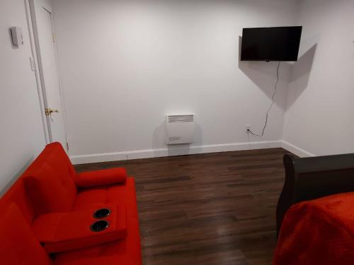 a living room with a red couch and a television at Motel LA RÉFÉRENCE in Trois-Rivières