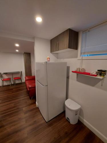 a kitchen with a refrigerator and a red couch at Motel LA RÉFÉRENCE in Trois-Rivières