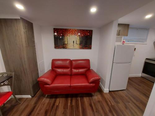 a red couch in a living room with a refrigerator at Motel LA RÉFÉRENCE in Trois-Rivières
