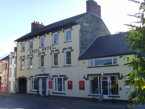 a white building with a black roof on a street at The Angel Hotel in Cardigan