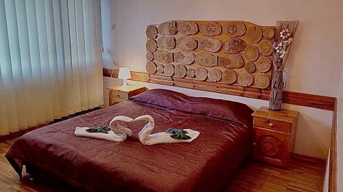 ein Schlafzimmer mit einem Bett mit zwei Handtüchern in Form von Schwänen in der Unterkunft Guest House Planinski Zdravets in Bansko