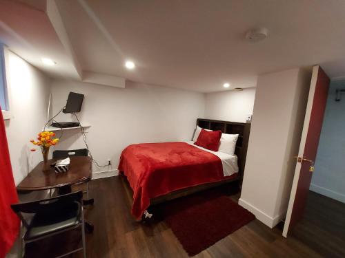 a bedroom with a bed with a red blanket and a desk at Motel LA RÉFÉRENCE in Trois-Rivières