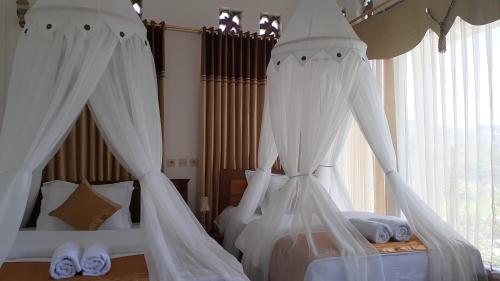 um quarto com 2 camas e redes mosquiteiras brancas em Bintang Bungalow Tour & Travel em Kelimutu