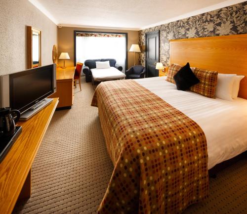 a hotel room with a bed and a flat screen tv at Mercure Bristol North The Grange Hotel in Bristol