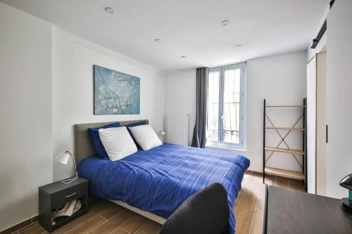 1 dormitorio con cama con sábanas azules y ventana en Le Nid de Montmartre, en París