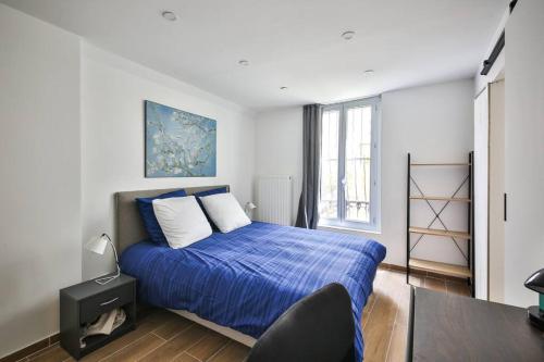 une chambre avec un lit avec des draps bleus et une fenêtre dans l'établissement Le Nid de Montmartre, à Paris