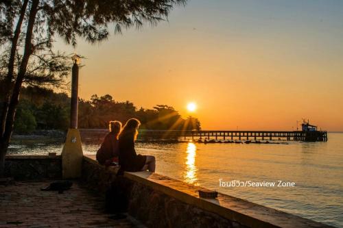 two people sitting on a wall watching the sunset at Issara Beach Resort in Sichon
