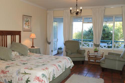 a bedroom with a bed and two chairs and a window at Yellowwood Lodge in Knysna