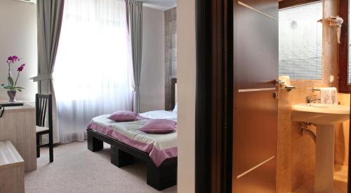 a small bedroom with a bed and a sink at Garni Hotel Vozarev in Belgrade
