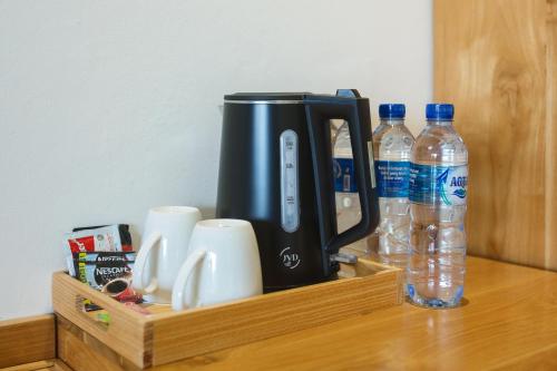 a black coffee maker on a wooden shelf with water bottles at Giriwood Hotel & Villa in Munduk
