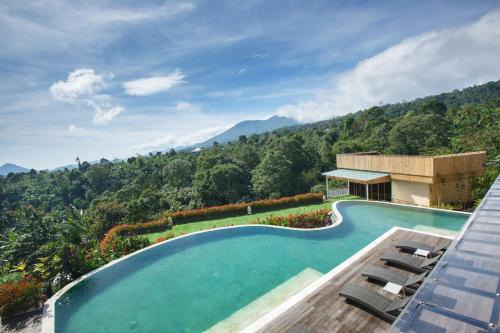 una imagen de una piscina con montañas en el fondo en Giriwood Hotel & Villa, en Bedugul