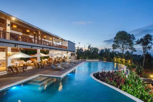 un hotel con una piscina con mesas y sillas en Giriwood Hotel & Villa en Bedugul