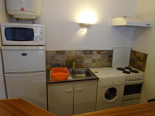 a small kitchen with a sink and a microwave at Fare Arearea Sweet Studio in Papeete