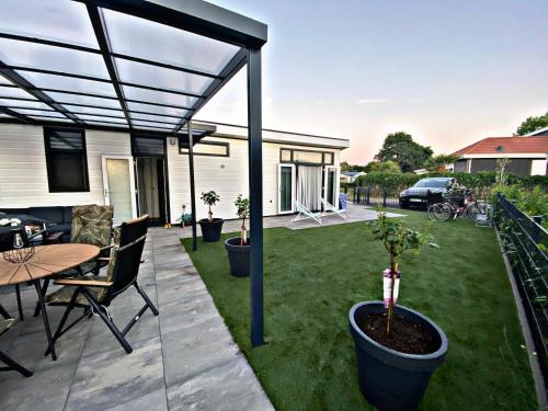 a patio with a table and chairs and a fence at Ferienhaus LuxChalet #VAJU Lathum# am See, Strand, Pool, Nationalpark in Lathum