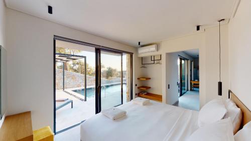 a bedroom with a white bed and a large window at DAELIA Villas in Plomarion