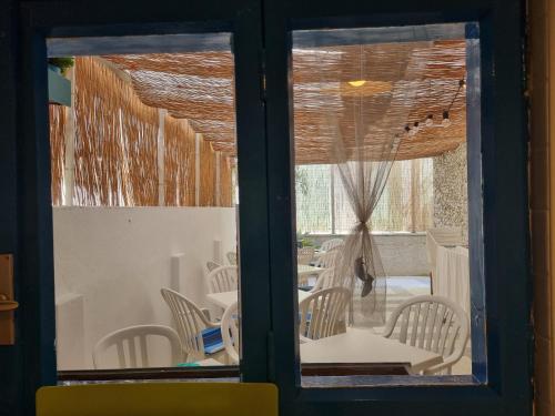una ventana con vistas a un comedor con sillas y mesas en Villa Lisa - La quiete e il profumo del mare, en Grado