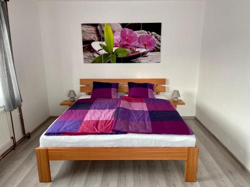 Apartmány Marjánka في Jenschowitz: غرفة نوم مع سرير بملاءات أرجوانية وأرجوانية