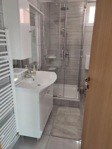a white bathroom with a sink and a shower at Kuća za odmor Balera in Šumarina