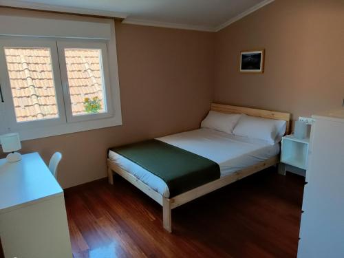ein kleines Schlafzimmer mit einem Bett und zwei Fenstern in der Unterkunft Rodeira in Cangas