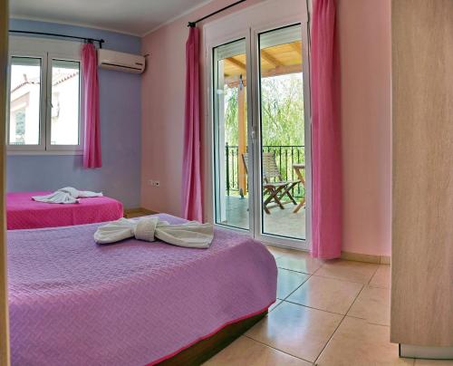 two beds in a room with pink curtains and a balcony at YAKINTHOS GARDEN in Mytilini