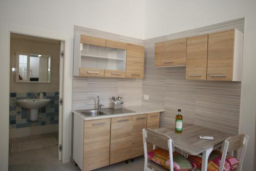 a kitchen with wooden cabinets and a table and a sink at Appartamenti Luce Vieste in Vieste