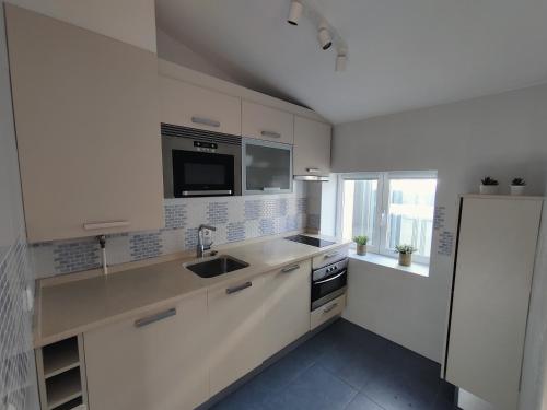 a white kitchen with a sink and a refrigerator at alMirante Burgos Centro Tranquila y con encanto Como en casa in Burgos