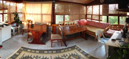 Habitación con mesas, sillas y ventanas de madera. en Keramos Pansiyon, en Finike