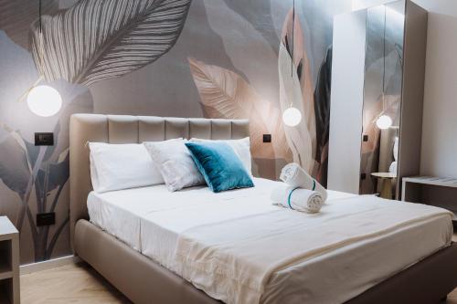 a bedroom with a bed with white sheets and blue pillows at Ammare rooms in Agrigento