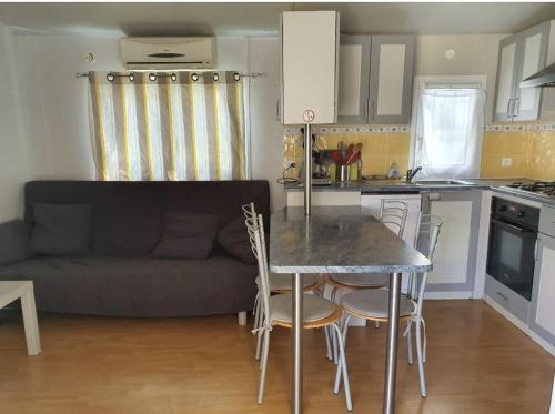 een keuken met een tafel en stoelen en een bank bij Camping LES PALMIERS in Hyères
