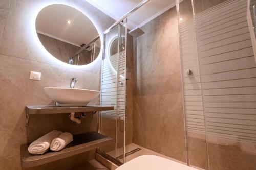 y baño con lavabo y ducha con espejo. en Dinos Apartments, en Vasiliki
