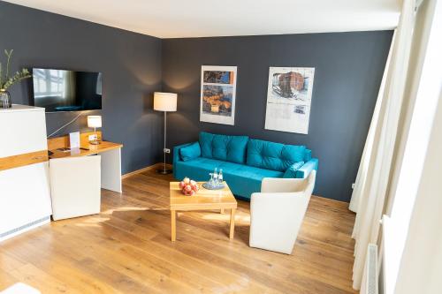 ein Wohnzimmer mit einem blauen Sofa und einem Tisch in der Unterkunft Schiefer Suite Hotel & Apartments in Goslar