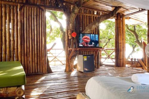 een slaapkamer met een bed en een televisie in een kamer met bomen bij Fincasa del Mar-La Casa del Arbol in Prado