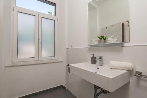 a white bathroom with a sink and a window at Lux Apartments in Rijeka