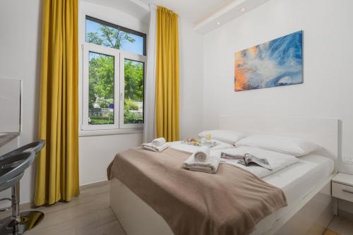 a white bedroom with yellow curtains and a bed at Lux Apartments in Rijeka