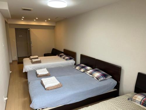 a room with two beds with towels on them at Atami Onsen Guest House Megumi 5 minutes walk from Atami Station in Atami