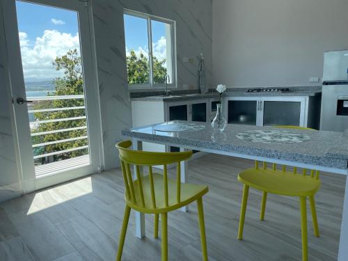 a kitchen with a table and two yellow chairs at Apartamentos La Torre in Río San Juan