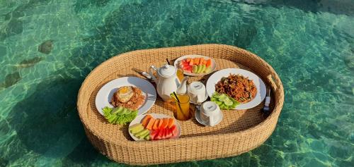 einen Tisch mit Teller mit Lebensmitteln auf dem Wasser in der Unterkunft Nana Villas Sidemen in Sidemen