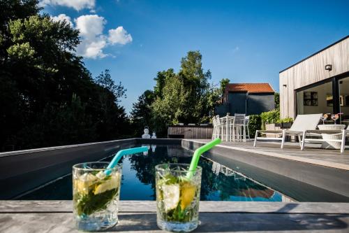 two drinks sitting on a table next to a swimming pool at Au Calme de Hosdent in Braives