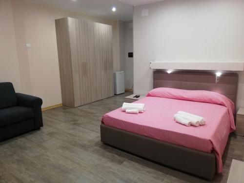 a bedroom with a pink bed and a black chair at Residenza Mediterranea in Zambrone