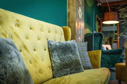 a yellow couch with pillows in a living room at Rezydencja Markowy Dworek in Białka Tatrzanska