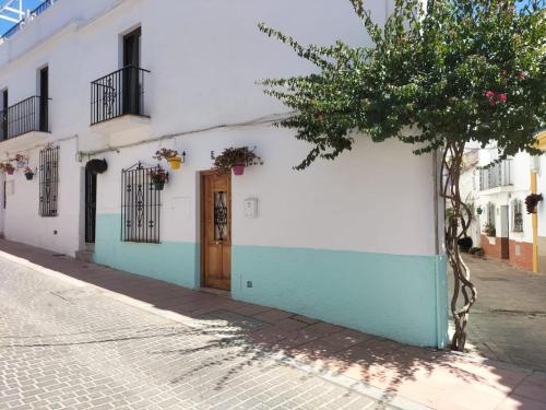 un edificio blanco y azul con una puerta en una calle en La Casita de Mari, en Estepona