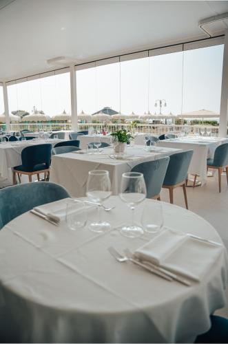 a dining room with white tables and chairs with glasses at Hotel Galassia Suites & Spa in Lido di Jesolo