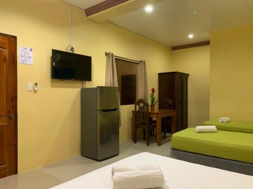 a room with a refrigerator and a tv on the wall at Mabini Hotel in Mambajao