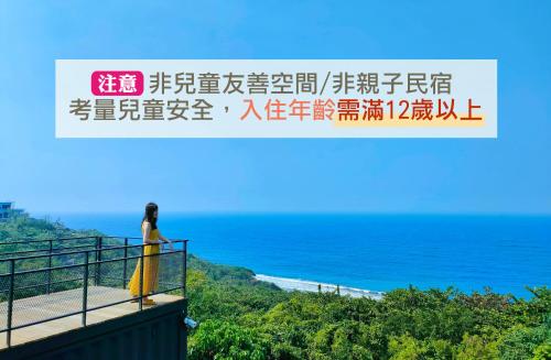 a woman standing on a balcony looking at the ocean at 濱境行旅 Begin Inn in Xiaoliuqiu